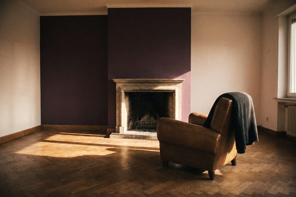 A deep plum feature wall framing a stone fireplace in a white room, with a leather armchair and grey throw